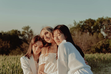 THREE HAPPY GIRLS EMBRACED IN THE COUNTRYSIDE. 