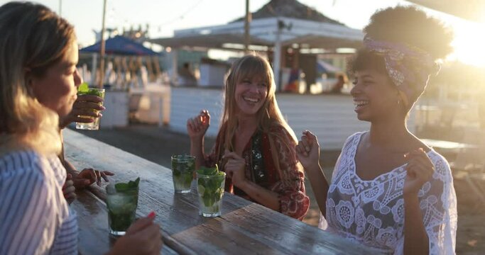 Happy girls enjoy mojito drinks at beach bar party outdoor