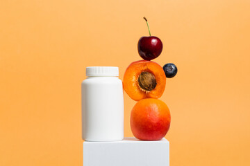 Multivitamin bottle of vitamins or pills with fresh fruits on orange background, bio supplement,...