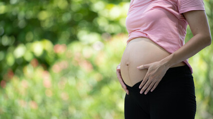 Pregnant woman touching belly in the City Park, Pregnant Relaxing and exercise, Beautiful tender mood photo of pregnancy