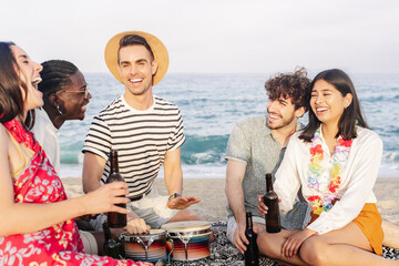 Group of friends singing on the beach. Multicultural group of teenagers and young adult people...
