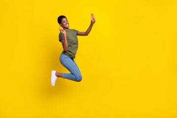 Fototapeta na wymiar Full length portrait of crazy person blogger make selfie show v-sign jump isolated on yellow color background