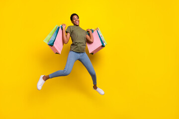 Fototapeta na wymiar Full length portrait of crazy excited person jump hold packages isolated on yellow color background