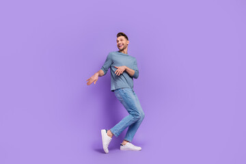 Fototapeta na wymiar Photo of dreamy charming guy dressed grey shirt looking empty space dancing isolated purple color background