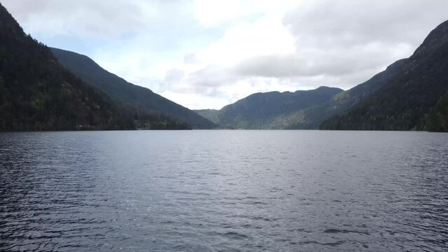 A low flying drone video over a lake between two mountains on a sunny day. Located in Parksville, Vancouver Island, Canada.