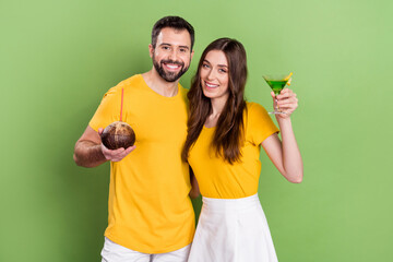 Photo of two carefree cheerful people hold alcohol cocktail toothy smile isolated on green color background