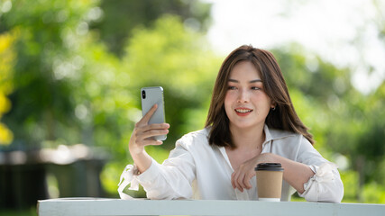 Thoughtful smile woman in park using smart phone, Portrait of a young charming business woman checking online Business work on her smart phone outdoors in the park on soft green back ground