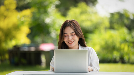 Thoughtful smile woman in park using smart digital tablet, Portrait of a young charming business woman checking online Business work on her smart tablet or labtop  outdoors in the park on soft screen 