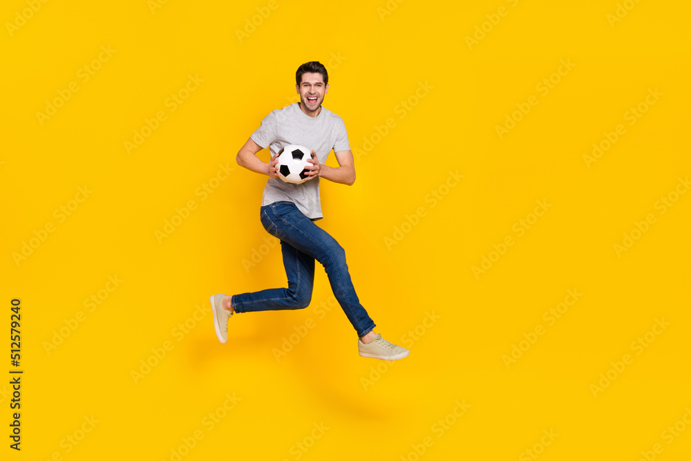 Poster full length body size view of attractive cheerful guy jumping playing soccer isolated over bright ye