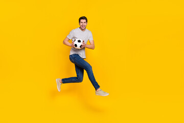 Fototapeta na wymiar Full length body size view of attractive cheerful guy jumping playing soccer isolated over bright yellow color background