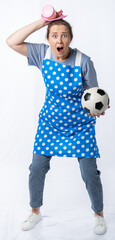 european housewife in kitchen apron holding aerosol can, napkin and soccer ball on white background, full length portrait. woman watching football and working at home