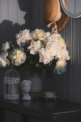 A beautiful white bouquet of peonies in the sunlight on a black table. The interior of a country...
