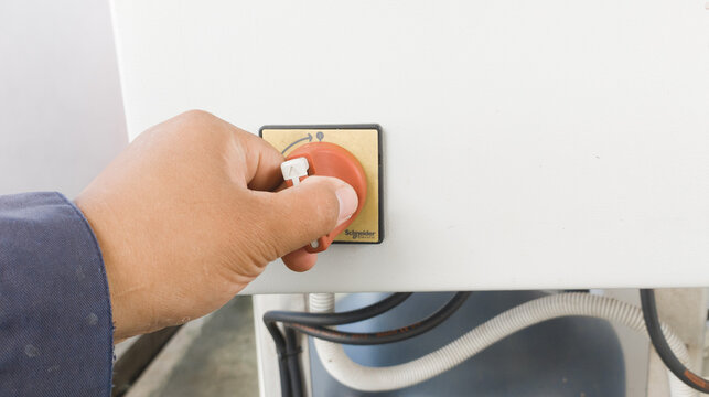 The man turning on main switch on panel control.