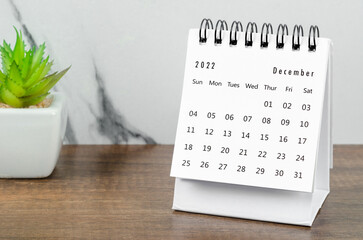 December 2022 desk calendar with plant pot on wooden table.