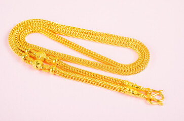 Gold necklace on pink background.