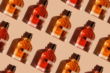 Pattern of different perfume bottles on a pastel beige background in the sunlight. Flat lay, top view. Luxury presentation mockup. Red, yellow and orange samples of aroma water