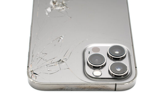 Close up of modern smartphone with broken back glass on white background.
