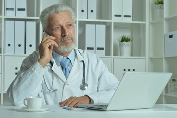Fototapeta premium Confident senior male doctor with stethoscope working in office