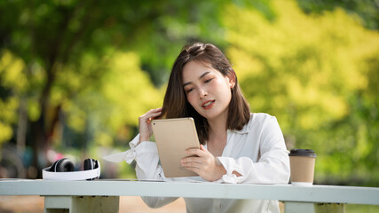 Shopper smile girl buying online or working online with a Smart Phone and credit card sitting on bench in a City Park in summer, Smile girl happy with her card, portrait of an executive young 