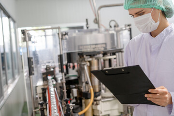 Quality control engineers work in the production and bottling facility for fruit juice or medicine....