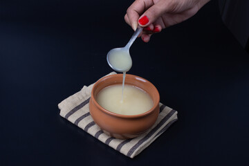 Pure cow ghee in ceramic bowl on black background with ghee spoon in hand