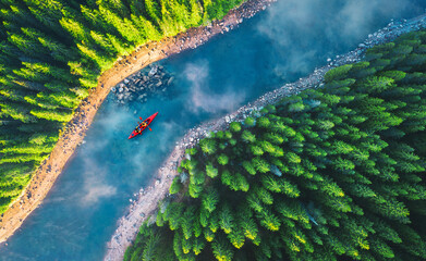 Aerial view of rafting boat or canoe in mountain river and forest. Recreation and camping - 512582254