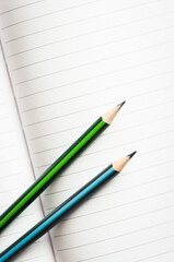 Open notebook papers with green and blue pencils.