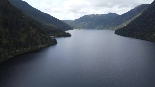 A tilting drone video revealing a lake between two mountains on a sunny day. Located in Parksville, Vancouver Island, Canada.