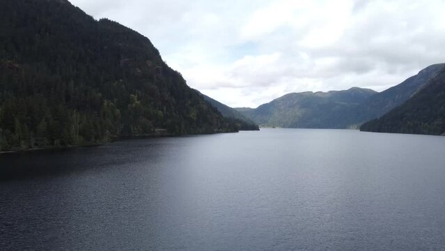 A panning drone video over a lake between two mountains on a sunny day. Located in Parksville, Vancouver Island, Canada.