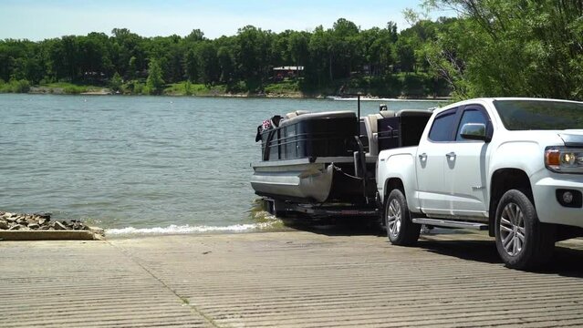 Unloading pontoon boat into the lake with white truck