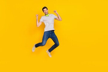 Fototapeta na wymiar Full length body size view of attractive cheerful lucky guy jumping listening hit rejoicing isolated over bright yellow color background