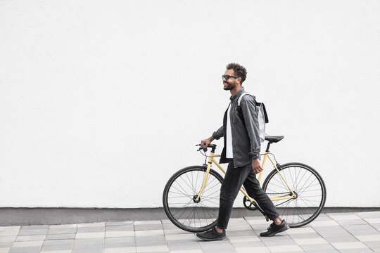 Young handsome man with bike over white wall background in city, Smiling student man with bicycle smiling outdoor, Modern healthy lifestyle, travel, casual business concept