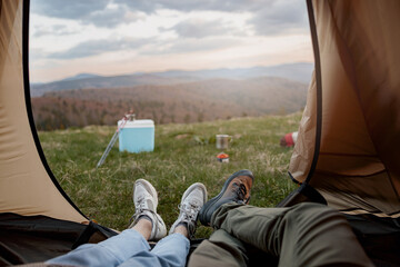 View from inside the tent on beautiful landscape of mountains. Couple lying in camp at nature.