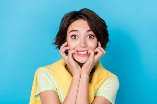 Photo of funny scared woman wear green t-shirt biting fingers big eyes isolated blue color background