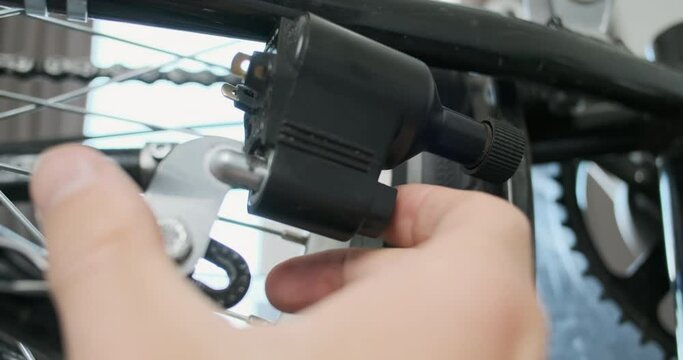 Man hand turns on bicycle dynamo. Put bike dynamo closer to the tire. Close-up, pedal movement, indoors.