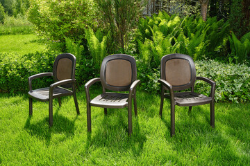 Fototapeta premium Chairs in the garden. Plastic chairs in ornamental garden background. Selective focus.