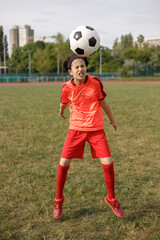 Girl teenage soccer player practicing jumping with the ball