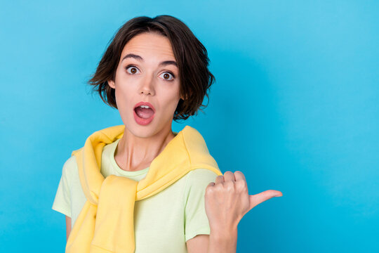 Photo of impressed young brunette lady indicate promo wear green t-shirt jumper isolated on blue color background