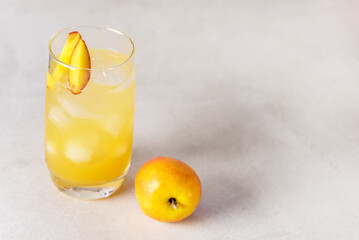 Summer Cold Drinks: Homemade Peach Lemonade with Ice Cubes in Glass on Gray Background Copy Space