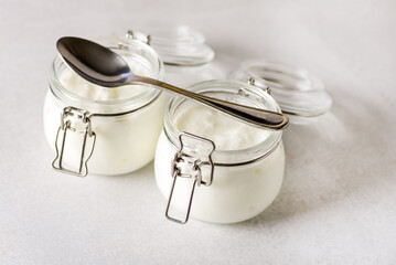 Two Portions of Fresh Natural Homemade Organic Yogurt in a Glass Jar Spoon Gray Background