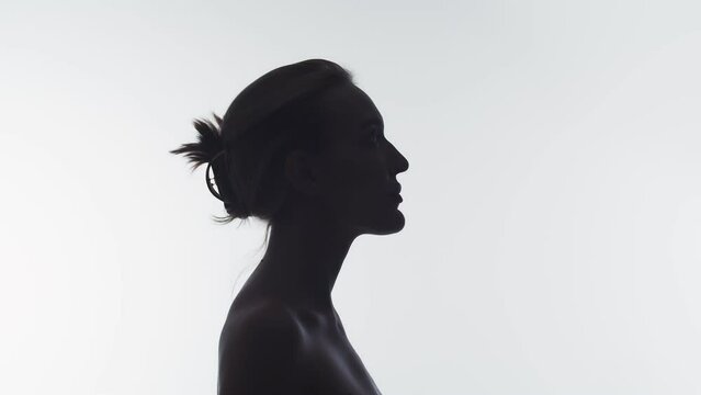 Portrait of a woman in profile raises her head and looks up, double exposure. The silhouette of a woman in profile raises her head and looks up