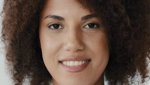Front view female smiling toothy perfect dark skin natural make-up face. Close up African American curly woman girlfriend biracial lady look at camera open and confident smile with healthy white teeth