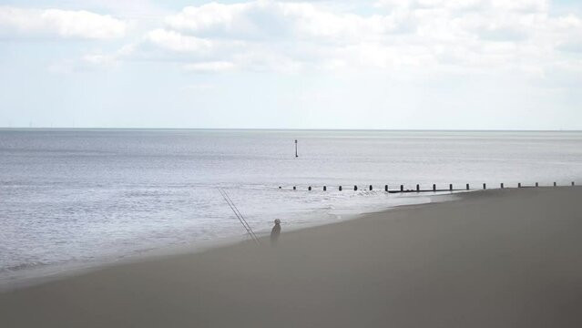 Wide shot of fishermen who is fishing from the beach side.