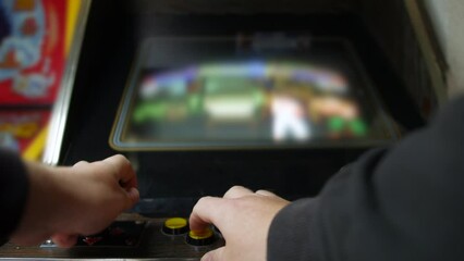 Close up of man playing a video game a retro vintage arcade machine. He is using the buttons and joystick to play