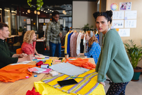 Portrait of confident caucasian female fashion designer with colleagues in office