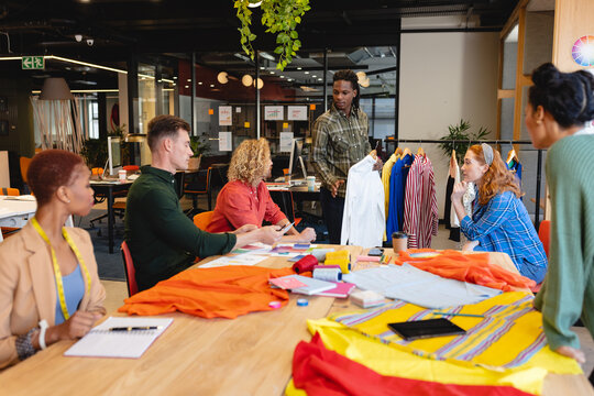 African American Male Fashion Designer Showing Garment To Multiracial Colleagues In Office