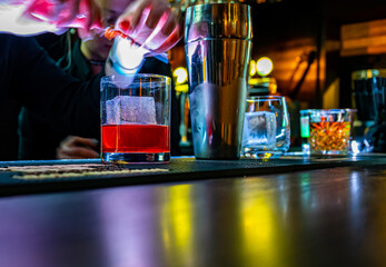 bartender hand making negroni cocktail. Negroni classic cocktail and gin short drink with sweet...