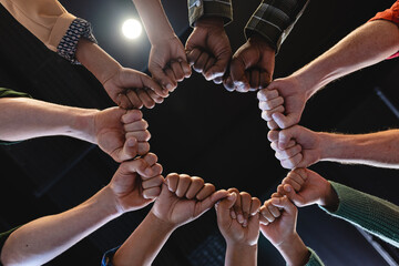 Directly below shot of multiracial fashion designers huddling with clenched fists in office