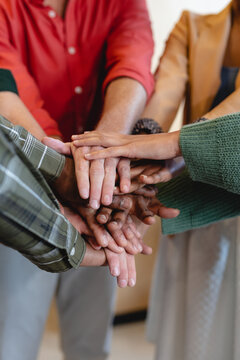 Midsection of multiracial fashion designers stacking hands in office
