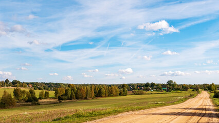 Rural landscape. A country road along the fields to the village. A clear day in early autumn